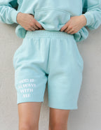 Light blue Elevated Faith Christian shorts with printed message 'God Is Always With Me' on the leg